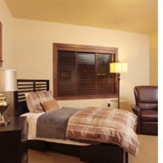 A cozy bedroom with a single bed, lamp, and armchair.