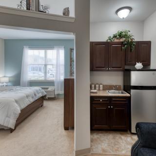 A cozy studio apartment featuring a bedroom and a compact kitchenette.