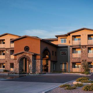 A modern three-story hotel building with a welcoming entrance and landscaped surroundings in the evening.