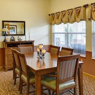 A cozy dining room with a wooden table and chairs, featuring a large window and decorative elements.