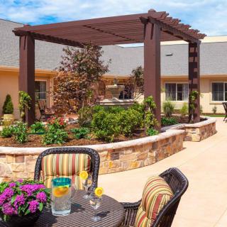 A cozy patio with a pergola, surrounded by a lush garden and outdoor seating.