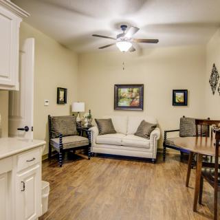 Cozy living room with a comfortable couch, chairs, and a dining table on wooden flooring.