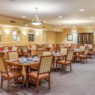 A nicely arranged dining area with multiple tables and chairs, well-lit by overhead lights.