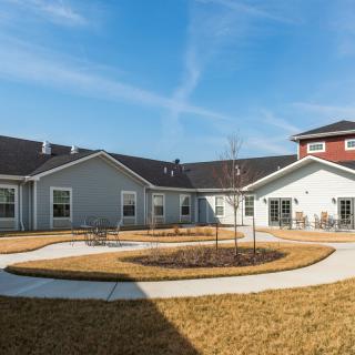 A residential building with a circular pathway and lawn under a clear blue sky.