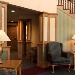 A cozy lobby area with armchairs, lamps, and a staircase.