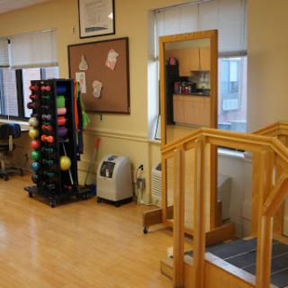 A well-equipped therapy room featuring a wooden ramp, exercise balls, and various fitness equipment.