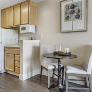 A compact kitchenette with a small dining area featuring wooden cabinets and minimalist decor.