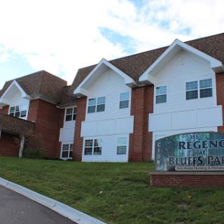 A view of a residential apartment complex with a brick facade and landscaped surroundings.