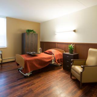 A well-lit hospital room featuring a bed, a comfortable chair, and minimalistic decor.