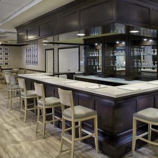 A modern bar interior with a sleek counter and seating arrangement.