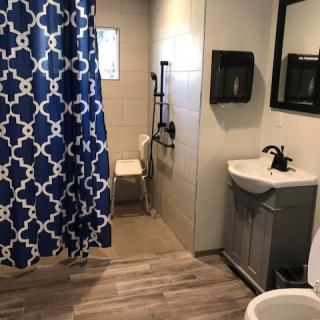 A modern bathroom with a blue patterned shower curtain and accessible features.
