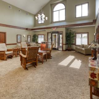 A spacious living room with high ceilings, decorated with comfortable furniture and natural lighting from large windows.