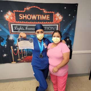 A nurse proudly displays her achievement alongside a supporter at a celebration event.