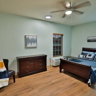 A cozy bedroom with a wooden bed, dresser, and modern decor.