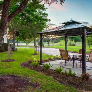 A serene outdoor patio area with a gazebo surrounded by lush greenery.