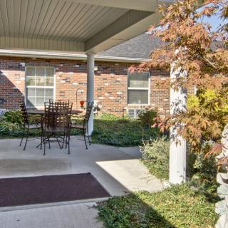 A cozy patio with outdoor furniture, surrounded by a brick building and garden.