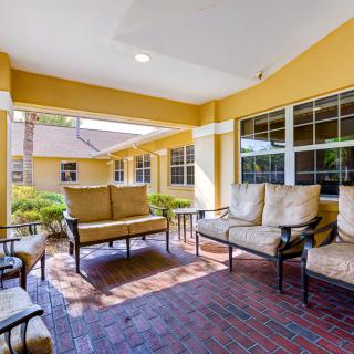 A cozy outdoor seating area on a covered patio with yellow walls and brick flooring.