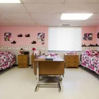 A children's hospital room with pink walls, two beds, and playful decorations.