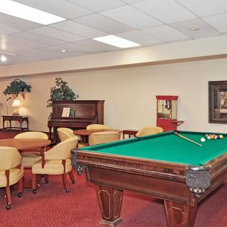 A recreational game room featuring a pool table, piano, seating area, and popcorn machine.