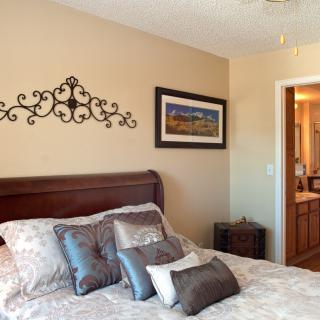 A cozy bedroom with decorative pillows and a wall hanging.