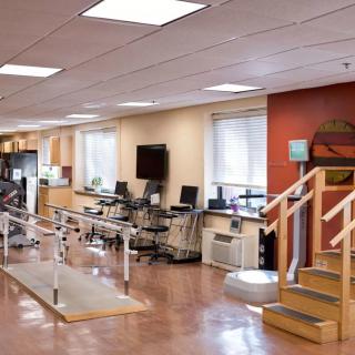 A physical therapy and rehabilitation room equipped with exercise machines and parallel bars.