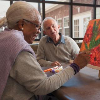 Elderly individuals enjoying a painting session together in an art class.