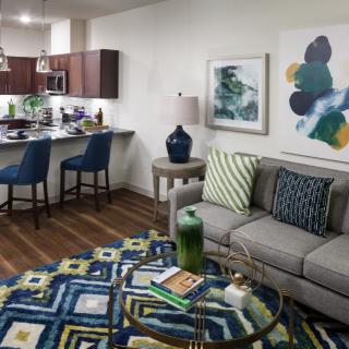 A modern open-concept living room and kitchen area featuring stylish furniture and vibrant artwork.
