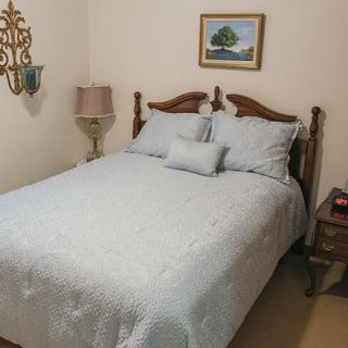 A cozy bedroom with a neatly made bed, decorative pillows, and elegant furnishings.