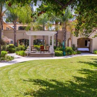 A serene garden with lush greenery, outdoor seating, and a building in the background.