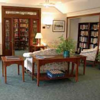 A cozy reading area in a library with wooden furniture and bookshelves.