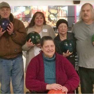 A group of people holding bowling balls poses together indoors.