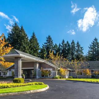 A modern building entrance surrounded by trees and a clear blue sky.