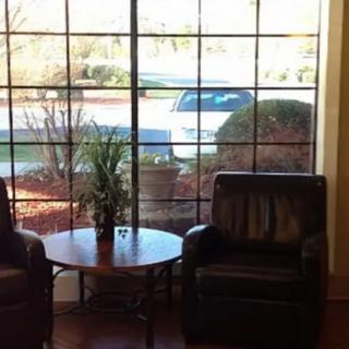 A cozy seating area with two chairs and a table beside a large window.
