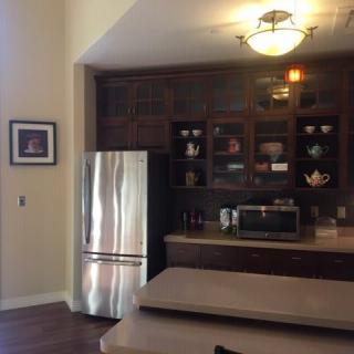 A cozy kitchen with dark wood cabinets, a stainless steel refrigerator, and a countertop with a microwave.