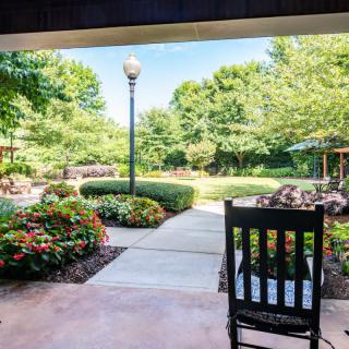 A serene garden view from a patio with a rocking chair.