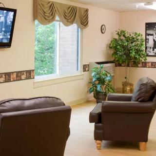 A cozy living room with comfortable chairs, a television, and indoor plants.