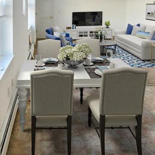 A cozy and modern living space featuring a dining table set for meals, a stylish sofa, and a television for entertainment.