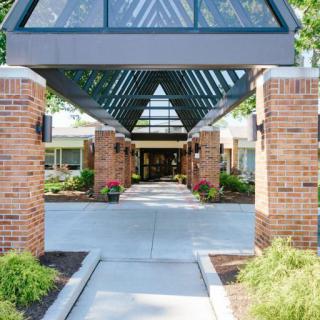 A covered entrance walkway with brick pillars and a glass roof leading to a building.