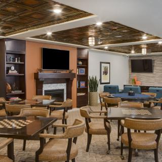 A cozy and stylish restaurant seating area with wooden tables, chairs, and a fireplace.