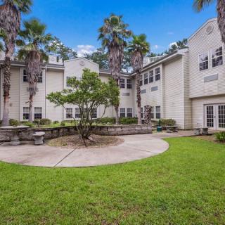 A serene courtyard with palm trees and well-maintained landscaping beside a multi-story building.