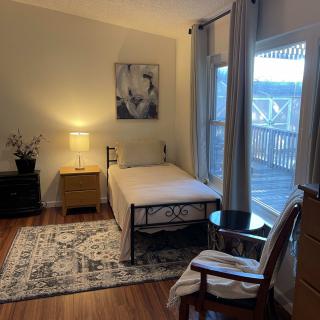 A cozy bedroom with a single bed, nightstand, and a window overlooking the outdoors.