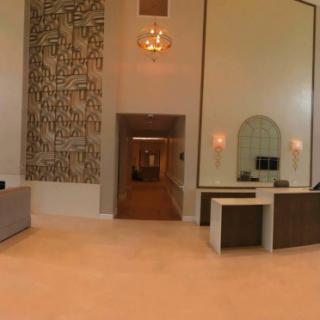 A modern lobby with a chandelier, reception desks, and decorative artwork.