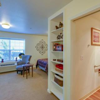 A cozy bedroom with an armchair and small table by the window, featuring a built-in bookshelf.