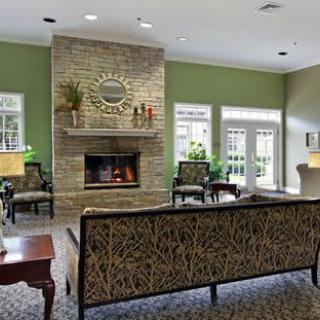 A cozy living room with a fireplace and ample seating, featuring modern decor and green walls.