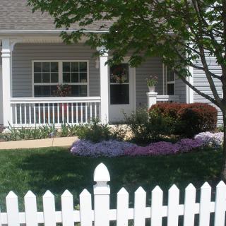 A charming single-story house with a white picket fence and a landscaped front yard.