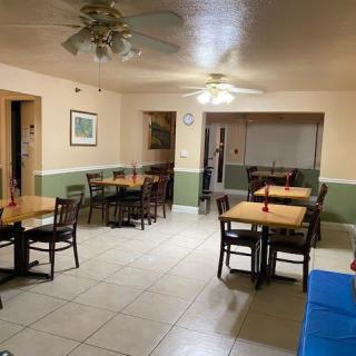 A dining area with multiple tables and chairs set up, featuring tiled flooring and ceiling fans.