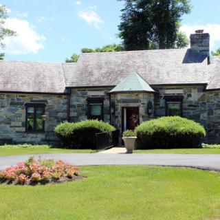 A charming stone house surrounded by lush greenery and colorful flowers.