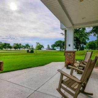 A peaceful porch view with rocking chairs overlooking a lush green lawn and trees.
