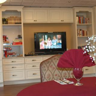 A cozy living space featuring a television, shelves filled with books, and an elegantly set dining table.
