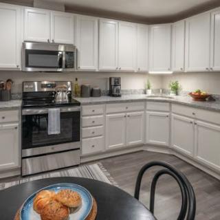 A modern kitchen featuring white cabinets and stainless steel appliances, with a cozy table set for enjoying cookies.